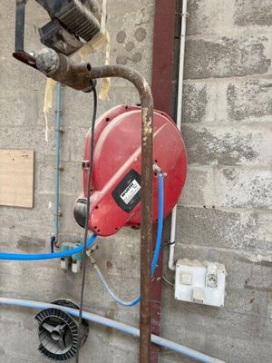 une borne d'incendie rouge et un tuyau bleu fixé au mur