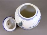 a white and blue vase with a lid sitting on a table