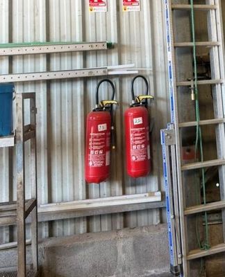 deux extincteurs accrochés au mur à côté d'une échelle
