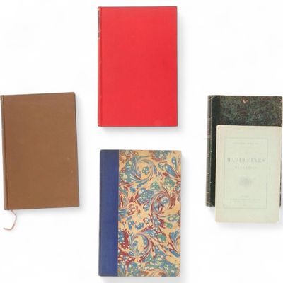 Plusieurs livres sont alignés sur une surface blanche, dont l'un a une couverture rouge.