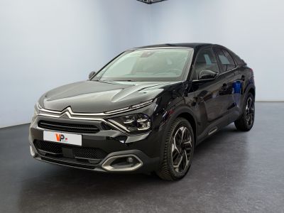 a black car parked in a large room with a clock on the wall