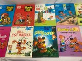 une pile de livres pour enfants posée sur un lit aux draps blancs