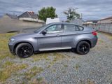 the bmw x6 is parked on the gravel in the yard