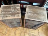 two speakers sitting on a wooden floor next to a bookshelf