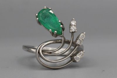 gros plan d'une bague avec une pierre verte et des diamants