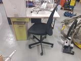 a desk with a chair and a vacuum in a room