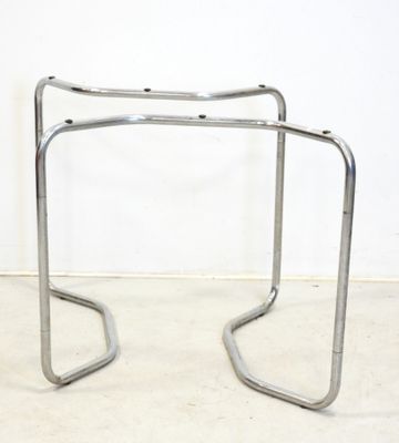 pair of chromed steel stools with curved legs in a white room