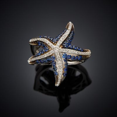 a close up of a starfish ring with blue and white diamonds