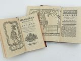 three old books are sitting on a white surface