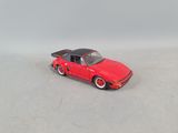 a red toy car that is on a white surface