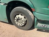 a green truck with a flat tire parked on the side of the road