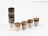 four silver cups are lined up in a row on a white surface
