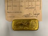 un lingot d'or posé à côté d'un ticket de caisse sur une table