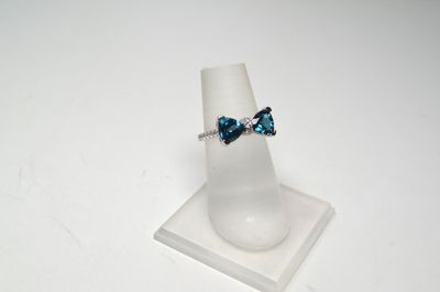 bague ornée de cristaux bleus et blancs, posée sur un support à bagues blanc