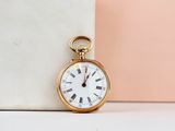 a gold pocket watch sitting next to a marble block