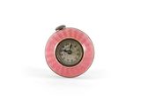 horloge avec un cadran rose sur fond blanc, posée sur une surface blanche