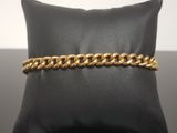 a gold chain bracelet on a black pillow