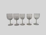 four empty wine glasses lined up in a row on a white surface
