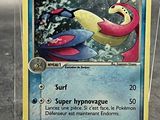 une carte Pokémon dans un étui en plastique posé sur une table