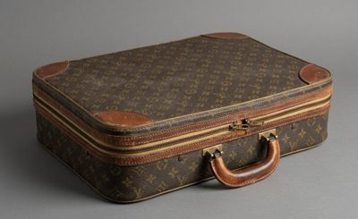 une valise marron et beige posée sur une surface grise