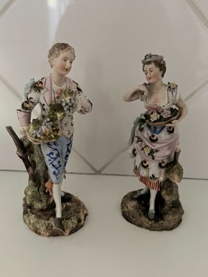 une paire de figurines représentant un homme et une femme tenant des fleurs