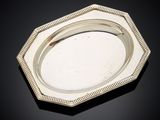an antique silver plate with beaded edge on a black surface