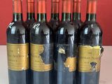 six bouteilles de vin rouge sont alignées sur un comptoir