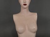 un mannequin féminin aux seins très volumineux exposé en vitrine