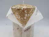 candle with a gold and white design on it sitting on a white surface