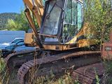 a yellow excavator that is sitting in the grass