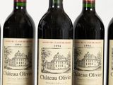 six bottles of red wine lined up on a wooden table