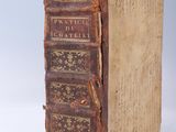 un vieux livre posé sur une table à côté d'un mur blanc