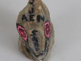a small rock with a face on it next to a price tag