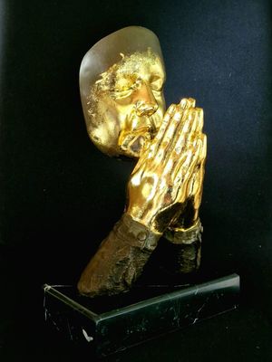 statue of a praying man with hands folded over his face