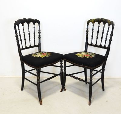 paire de chaises anciennes noires avec des coussins d'assise brodés de motifs floraux