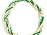 un gros plan d'un collier blanc et vert posé sur une surface blanche