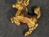 un pendentif en forme de cheval doré, fixé sur un tissu noir