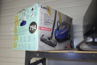 une boîte posée sur une étagère, avec un aspirateur à côté