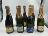 six bouteilles de champagne sont alignées sur une surface blanche
