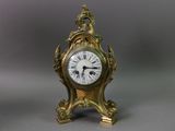 a small gold clock with a bird on top of it