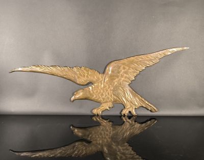 figurine d'un aigle royal posée sur une table noire, sur fond argenté