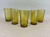 quatre verres jaunes alignés sur une surface blanche