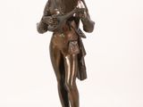 an antique bronze statue of a woman holding a basket