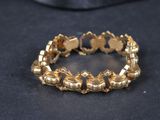gros plan d'un bracelet en or sur une surface noire