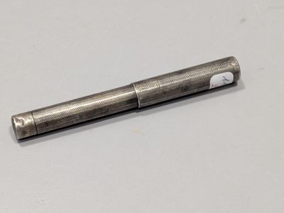 une image représentant un stylo en métal posé sur une surface blanche