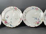 quatre assiettes ornées de motifs floraux sont alignées sur une surface noire