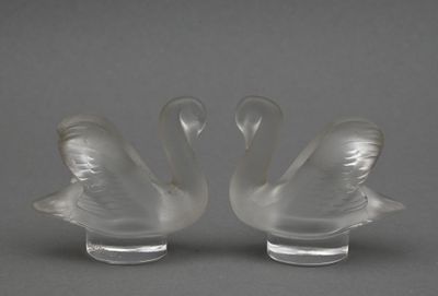 paire de figurines de cygnes en verre transparent sur un socle transparent