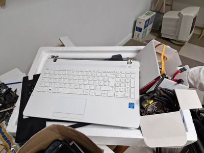 un ordinateur portable blanc posé sur une pile de bric-à-brac
