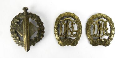 trois insignes en laiton comportant des initiales et une épée sur fond blanc