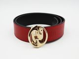La ceinture est rouge et noire, avec une boucle dorée.